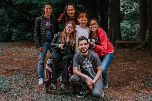 Group of friends smiling and posing with a camera in a forest setting, embracing diversity.